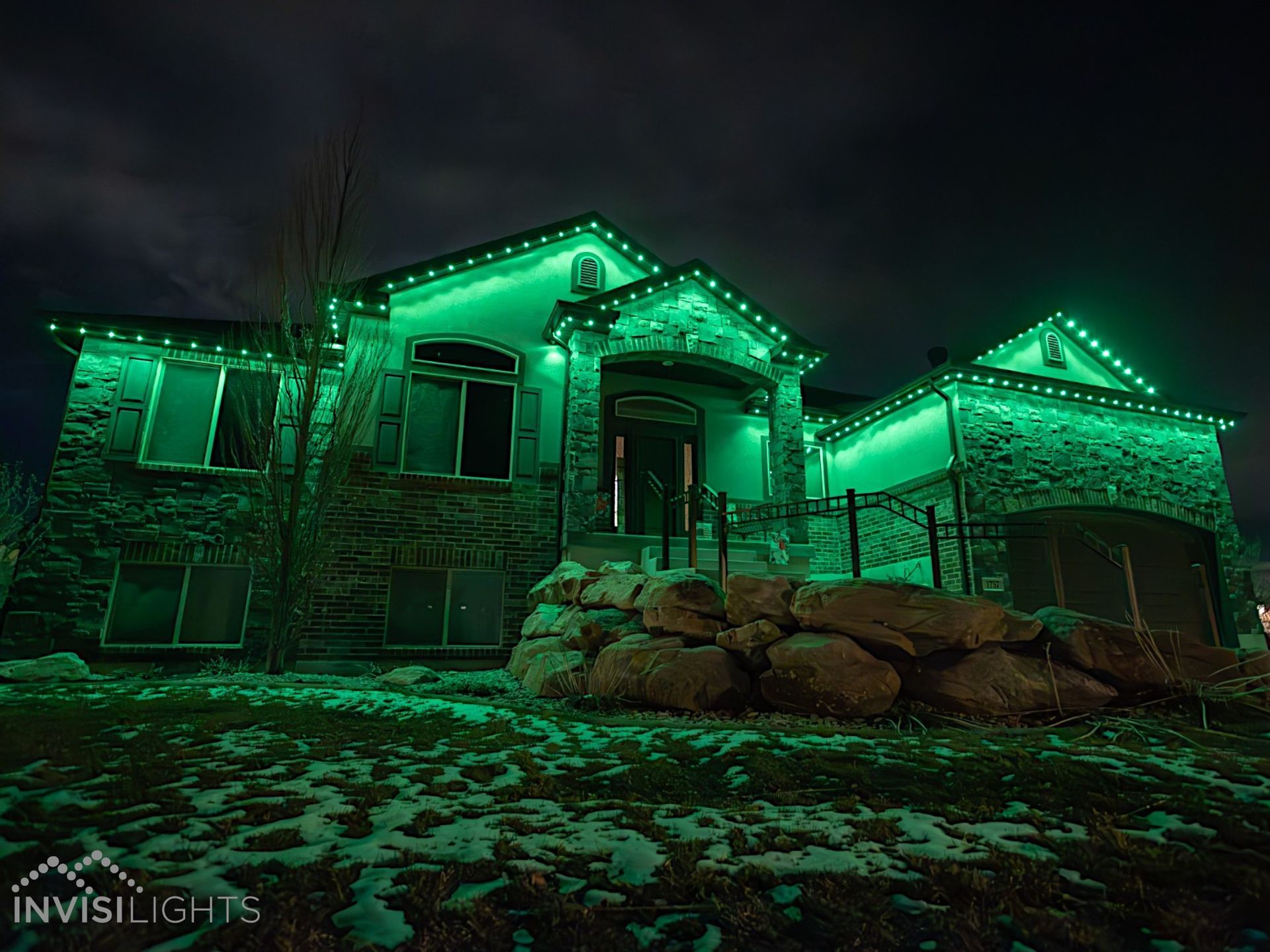 A large house is lit up with green lights at night.