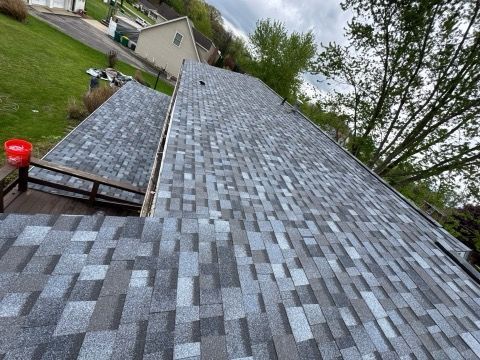 Roof with gray shingles on a house, viewed from above on a cloudy day.