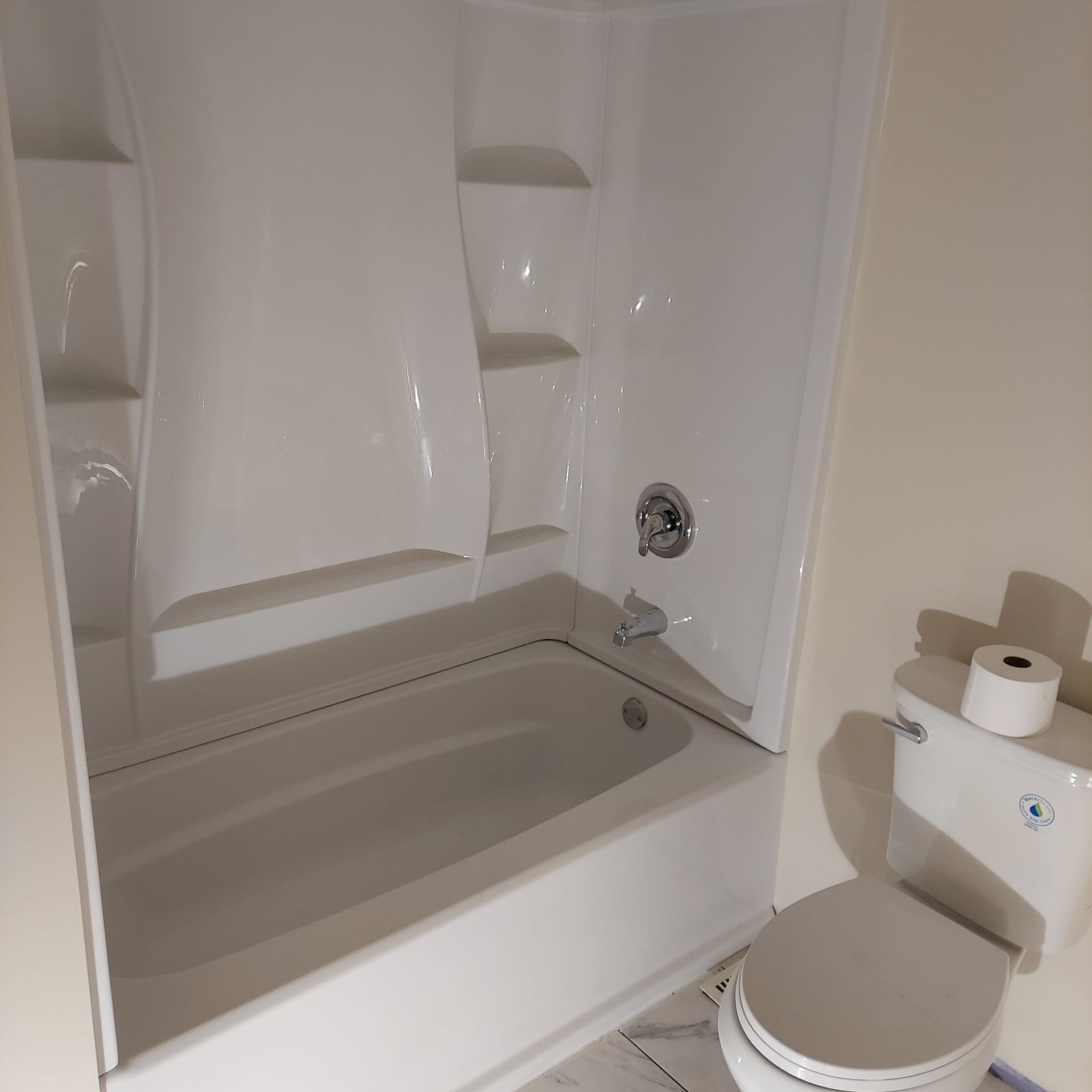 A bathroom with a toilet a bathtub and shelves
