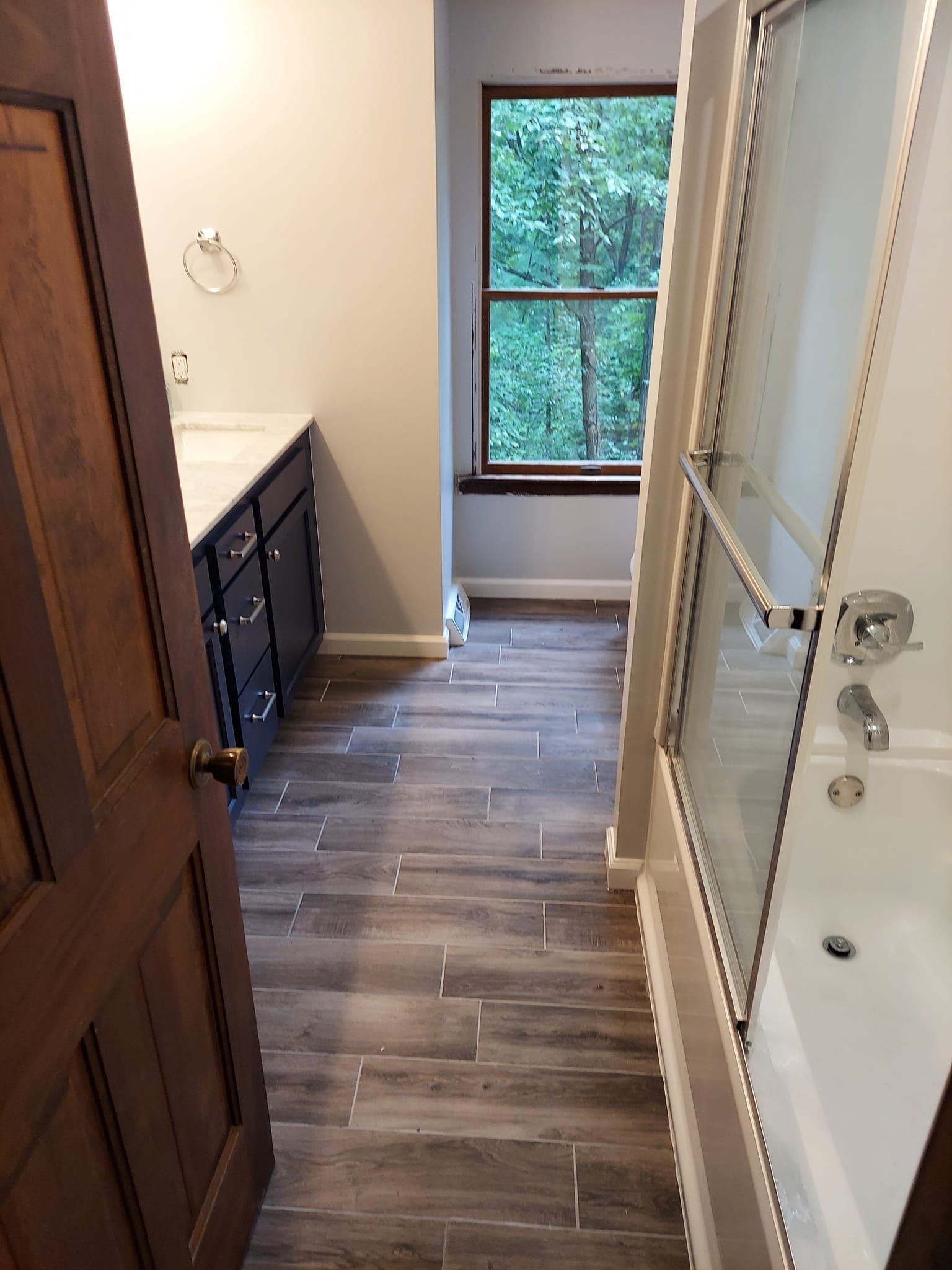 A bathroom with a tub , sink , and window.