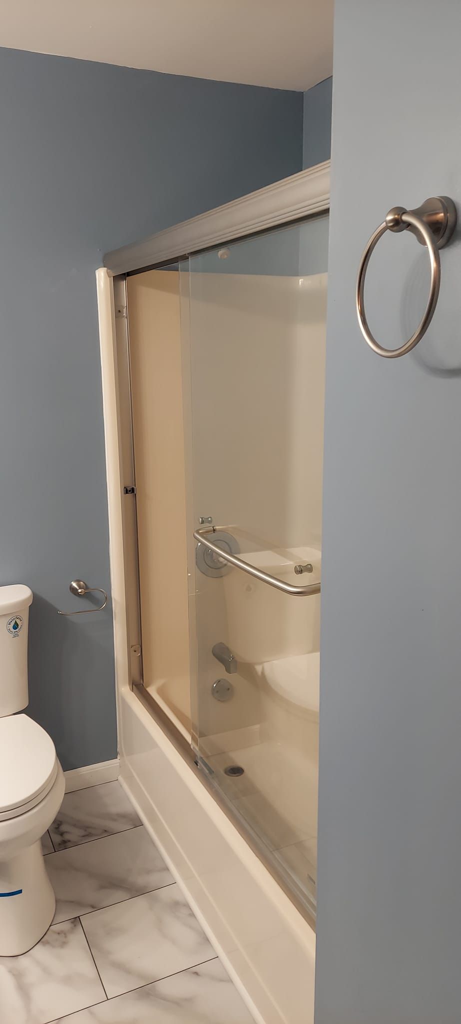 A bathroom with a toilet , shower , and towel rack.