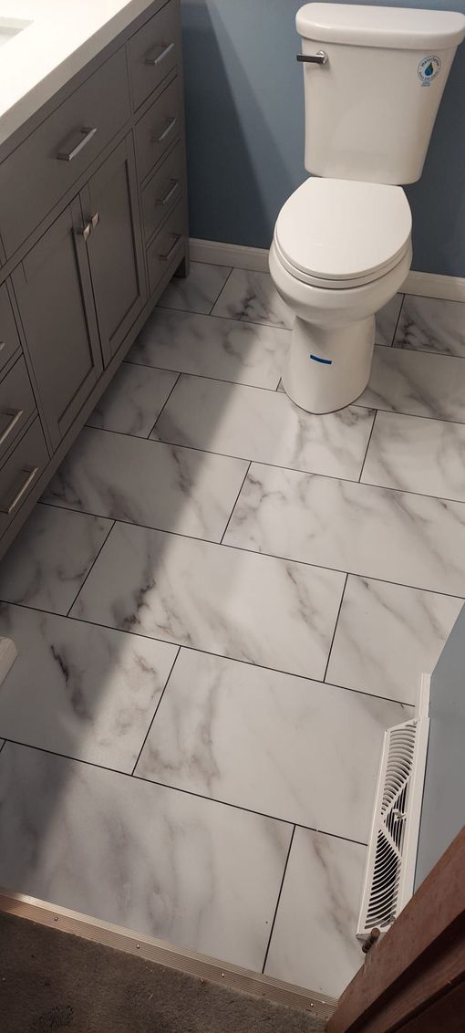 A bathroom with a toilet , sink , and marble floor.