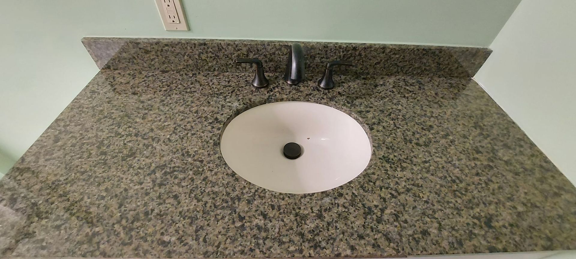 A bathroom sink is sitting on top of a granite counter top.