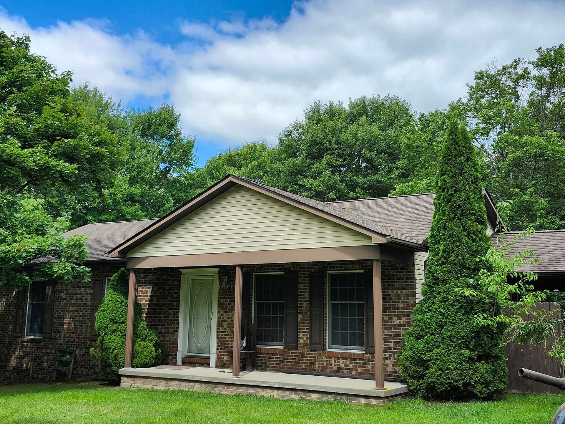 A small house with a porch and trees in front of it.