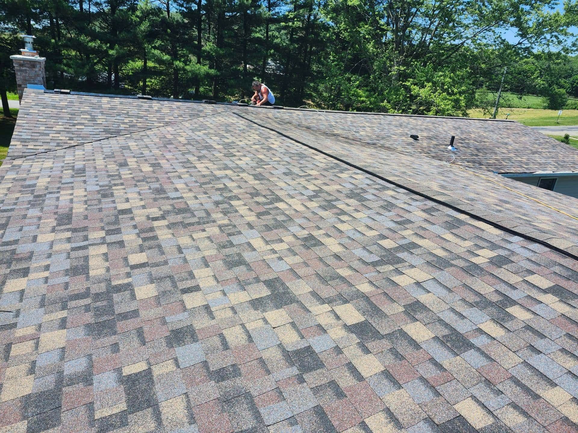 A roof with a lot of shingles on it and trees in the background.
