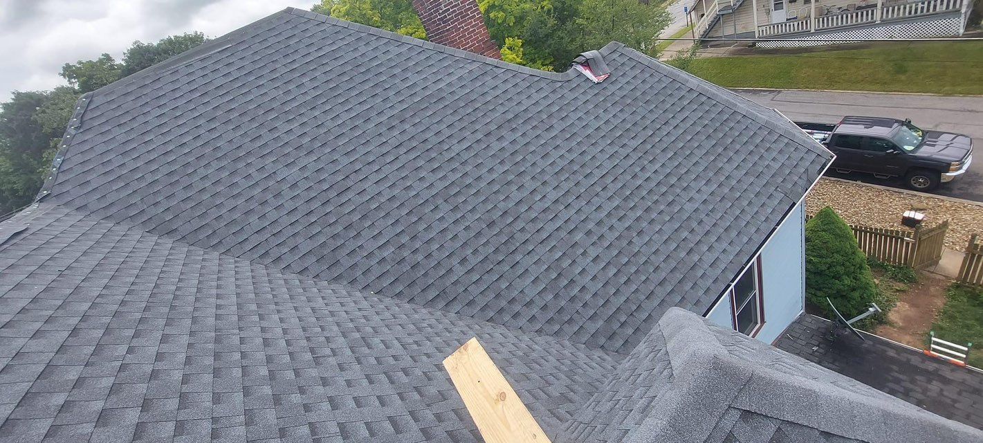 An aerial view of a roof with shingles being installed on a house.