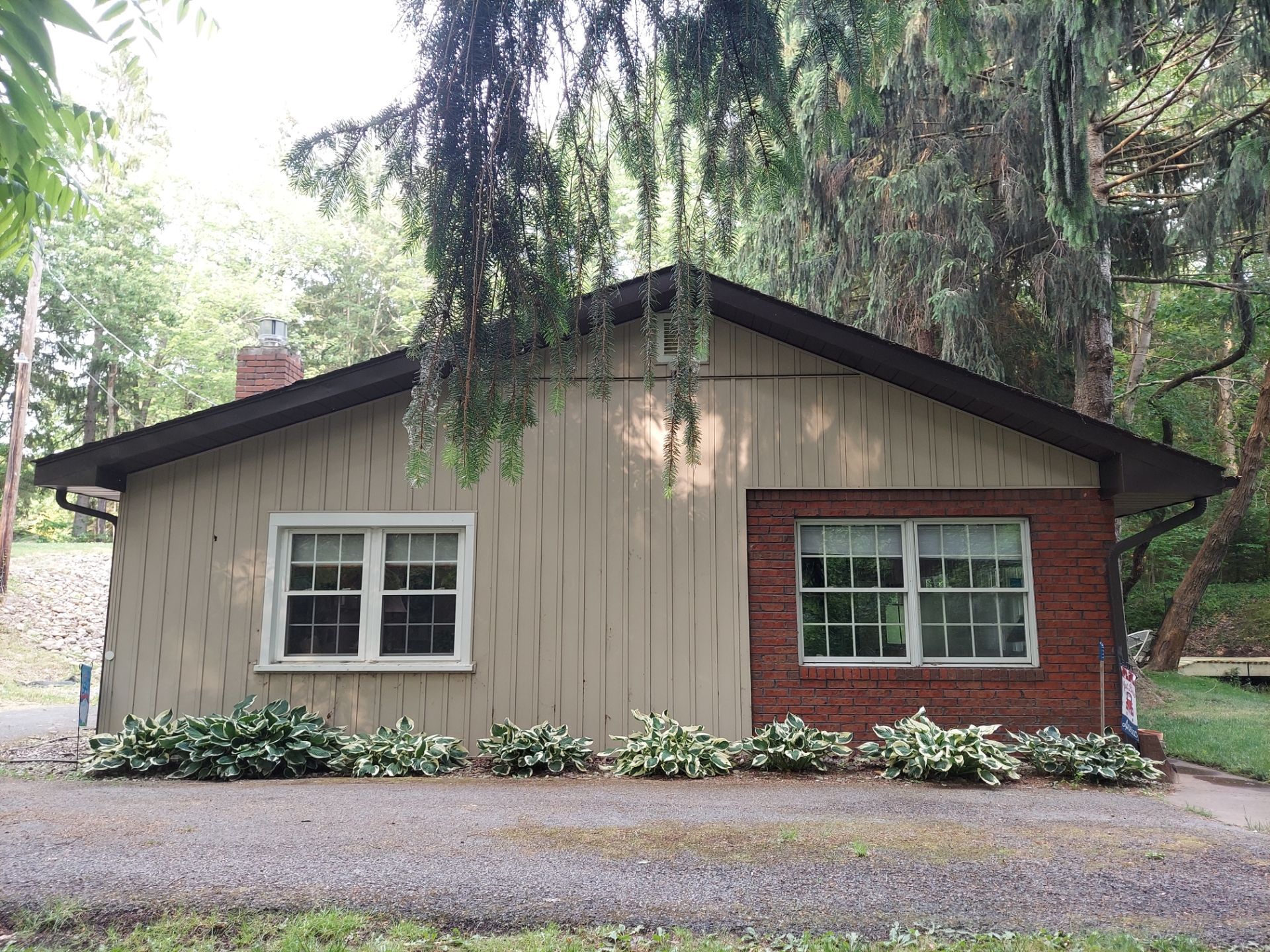 A small house with a brick wall and a tan siding