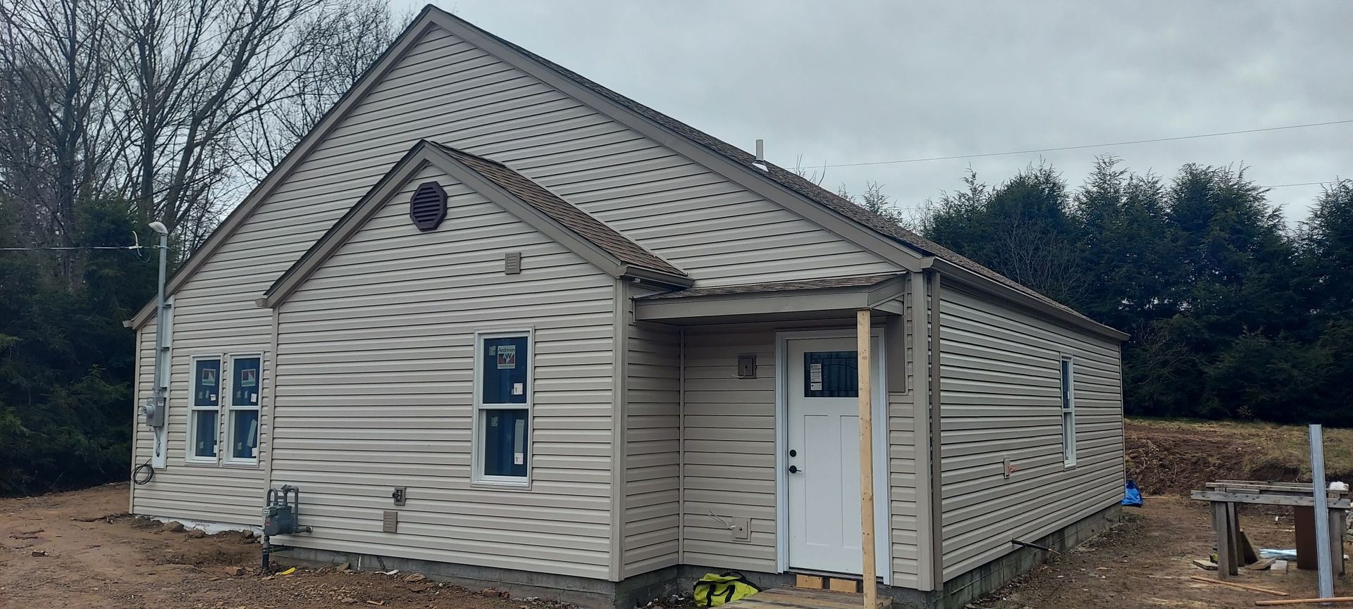A small house with a white door is sitting in the middle of a field.