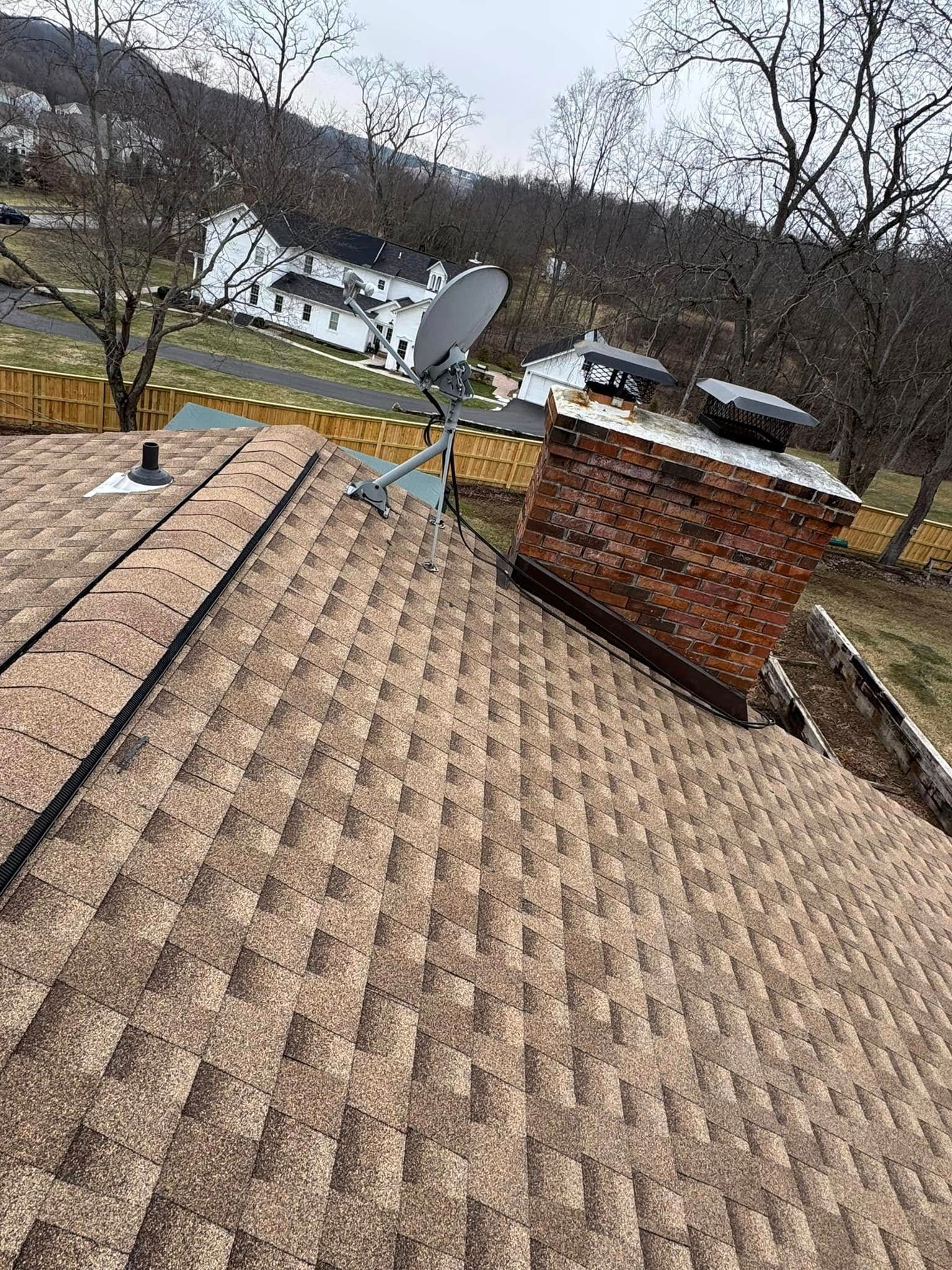 A roof with a chimney and satellite dish on it.