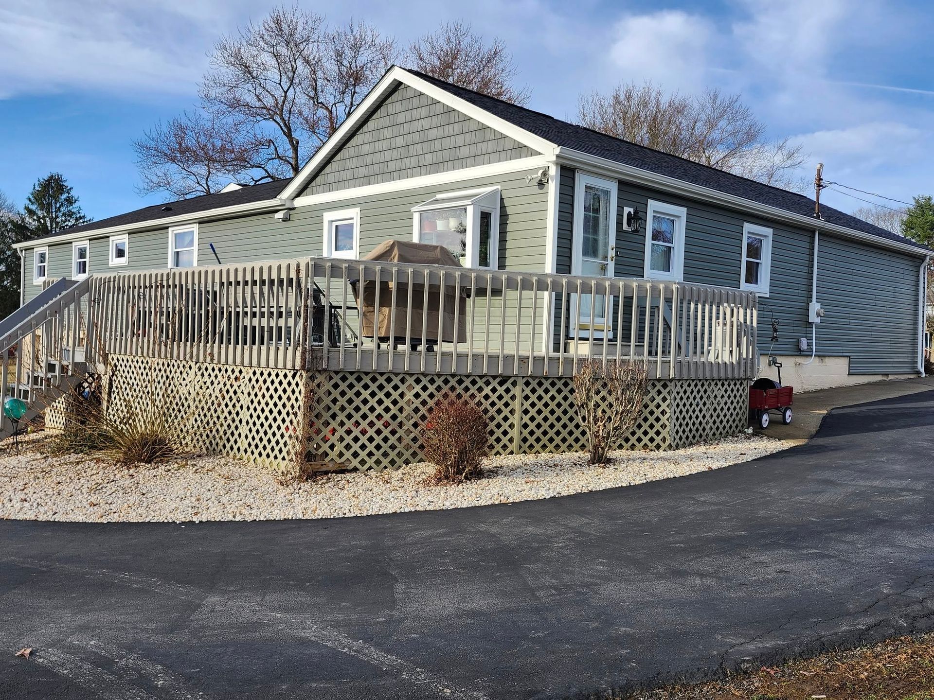 A large house with a large deck and a red wagon parked in front of it.