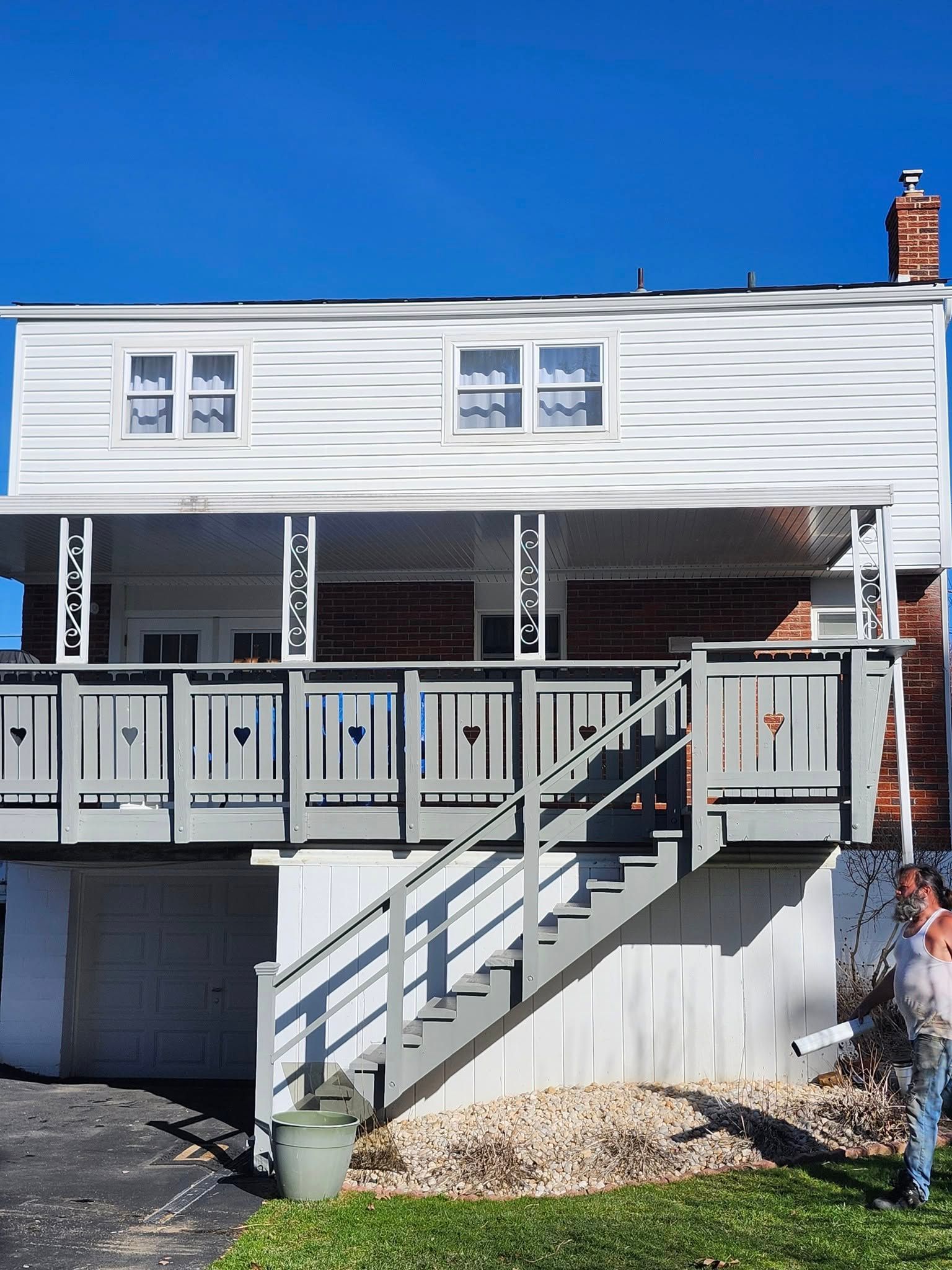 A man is standing in front of a house with stairs leading up to it.