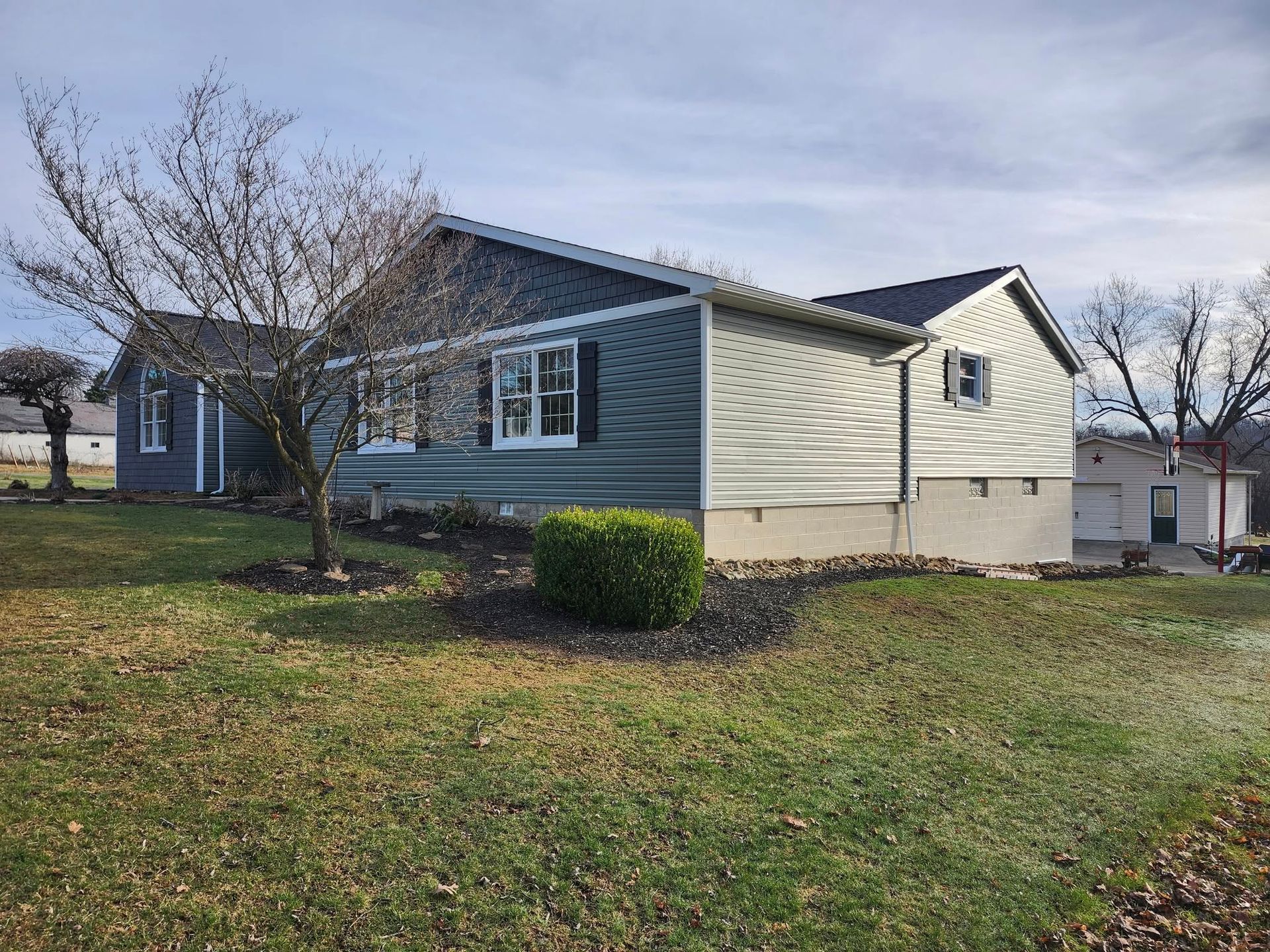 A house with a lot of windows is sitting on top of a lush green field.