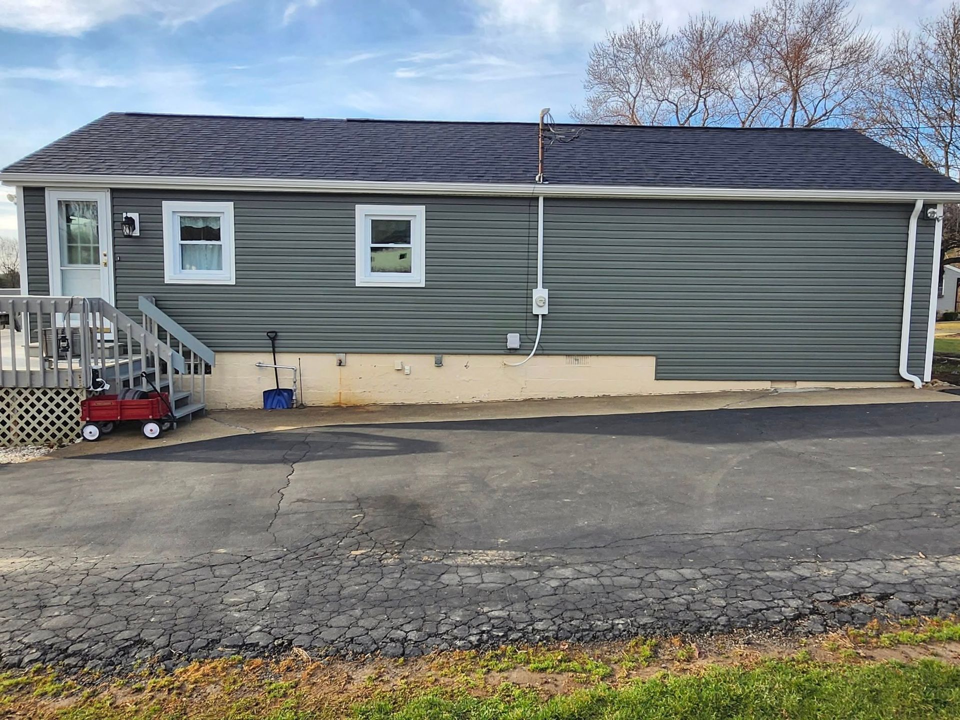 A small house with a red wagon parked in front of it.