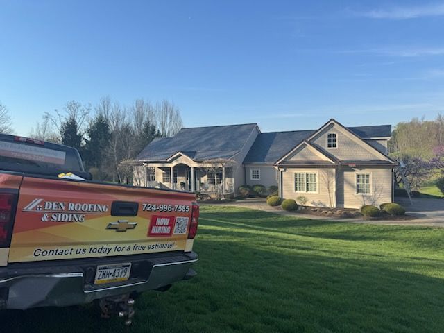 Red service van parked on a lawn beside a house with solar panels under a clear blue sky