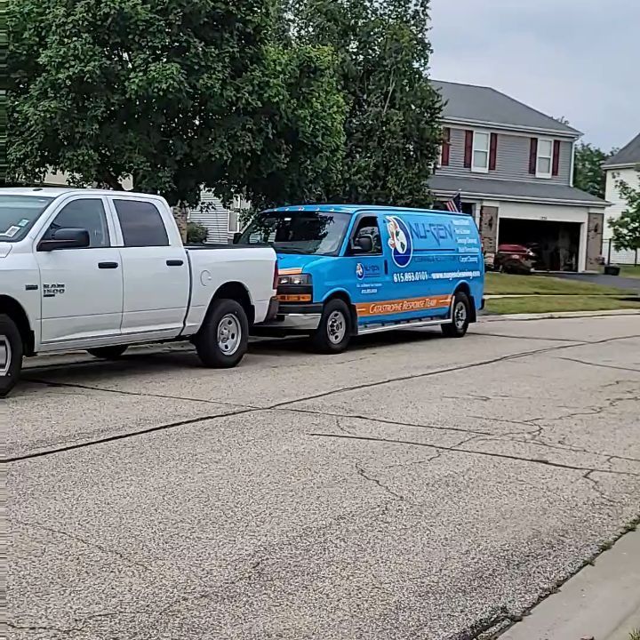 A white truck and a blue van are parked on the side of the road.