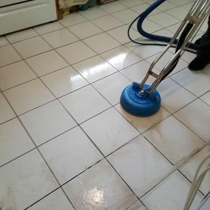 A blue vacuum cleaner is cleaning a tiled floor