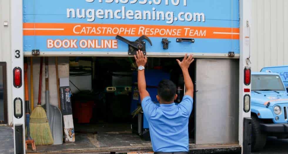 A man is standing in the back of a blue truck.