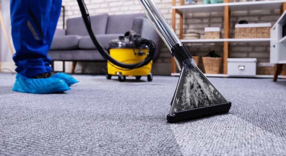 A person is using a vacuum cleaner to clean a carpet in a living room.