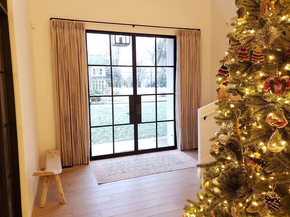 A door with custom drapery and a Christmas tree in the foreground.