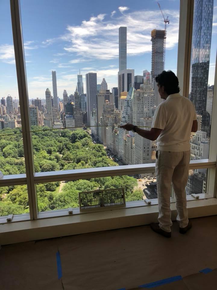A professional measuring a large glass window.