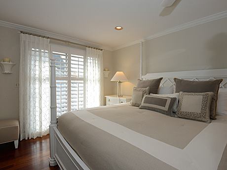A bedroom with custom shutters and sheer drapery