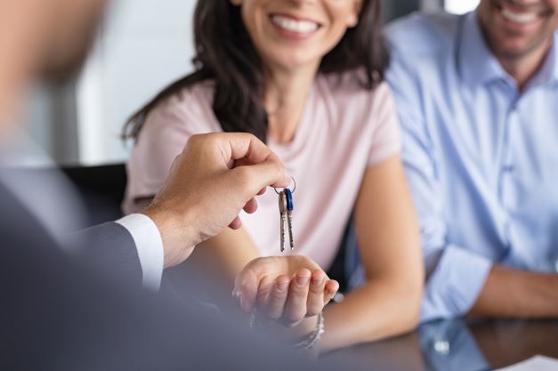 A man is giving a woman a set of keys.