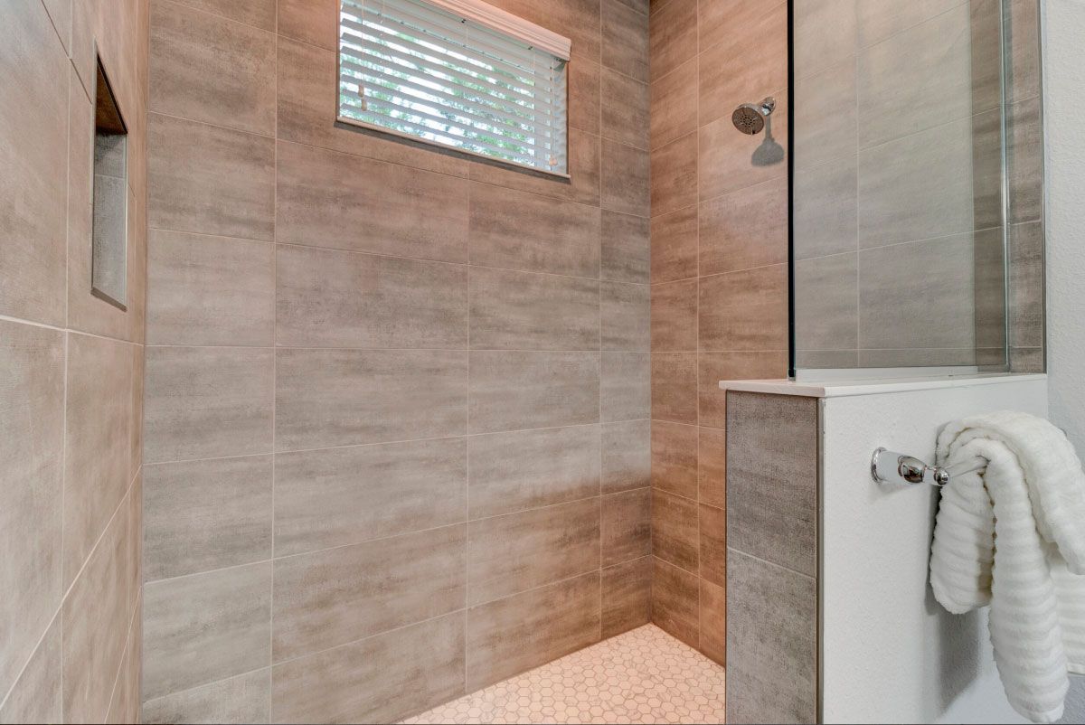 A bathroom with a walk in shower and a window.