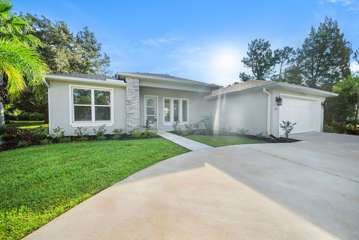 A white house with a driveway and a lot of windows