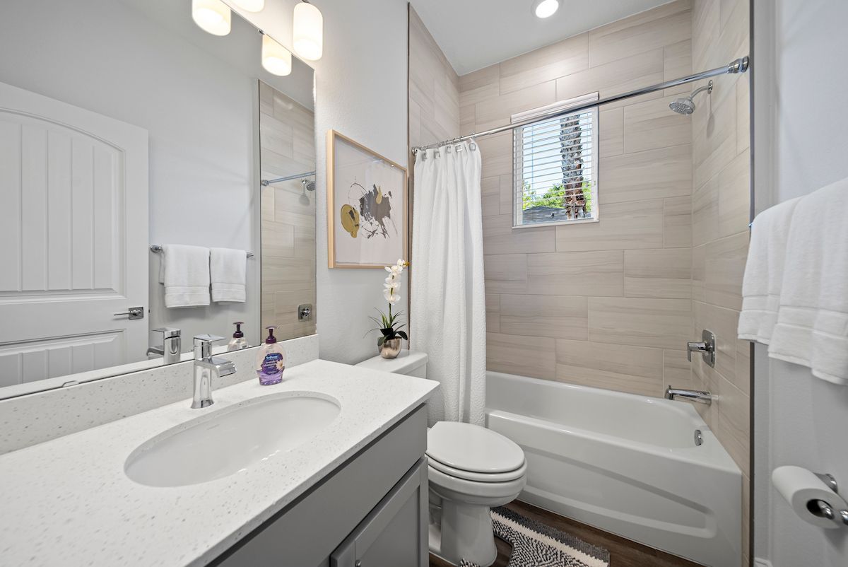 A bathroom with a sink , toilet , tub and mirror.