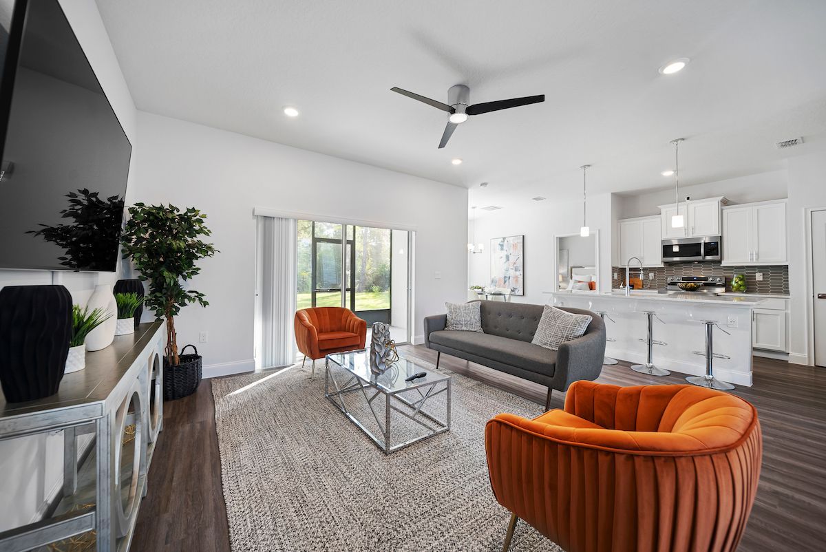 An openliving room with a couch, chairs, coffee table and television.