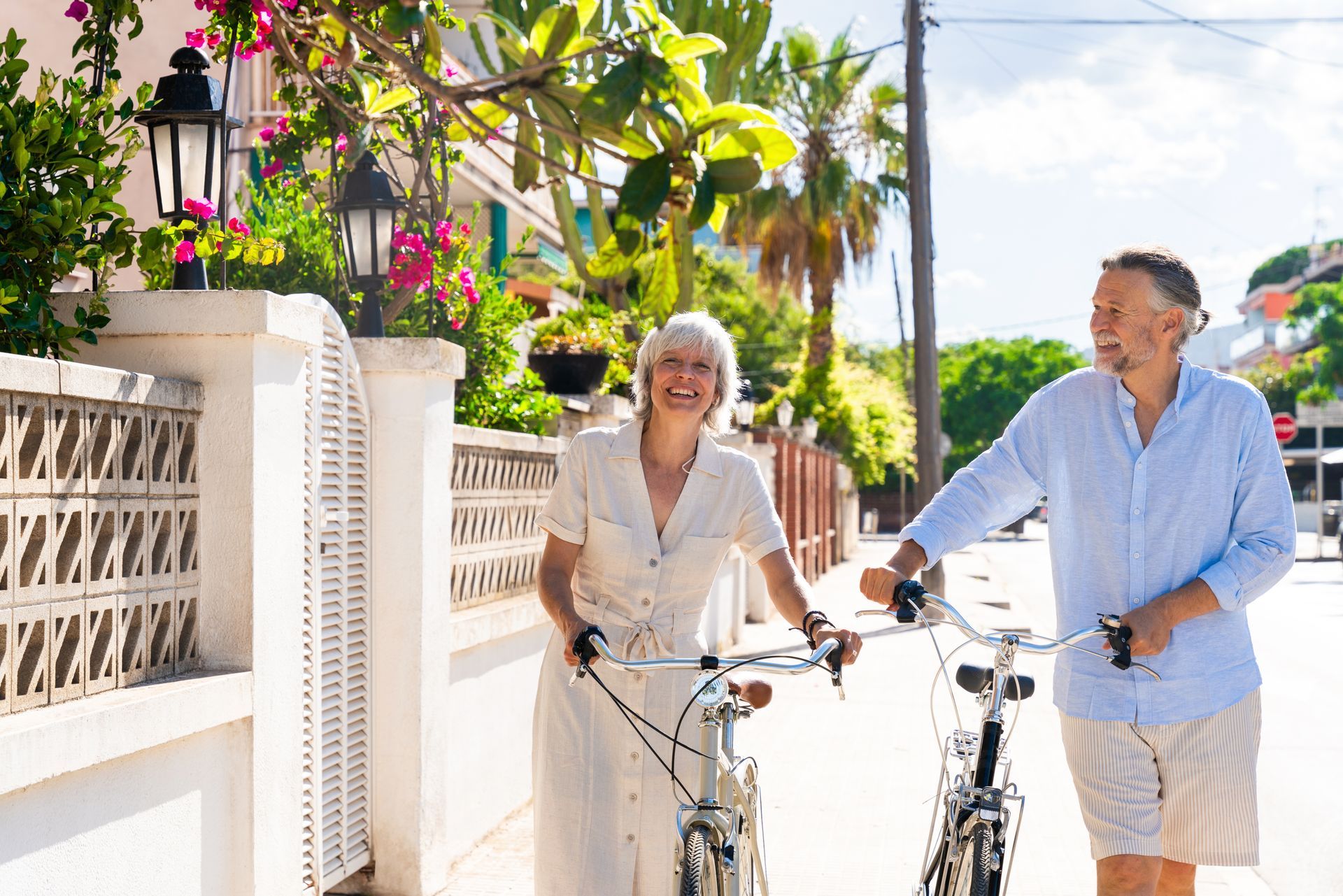 couple walking with their bicycles near the beach