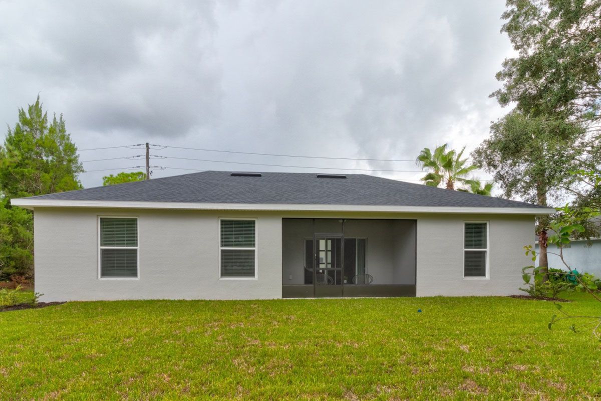 The back of a house with a screened in porch and a lot of windows.