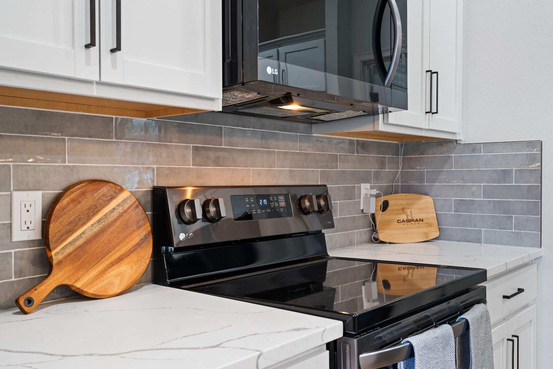 Modern kitchen with a sleek black electric stovetop and microwave, complemented by white cabinetry a