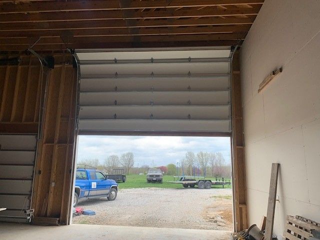 A blue truck is parked in a garage with the door open.