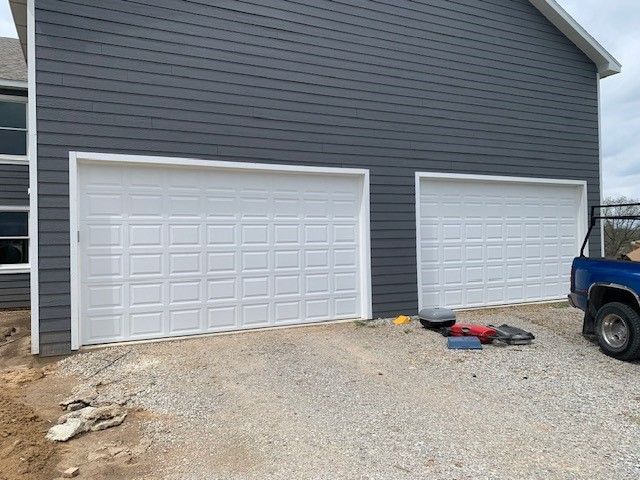 A blue truck is parked in front of a garage door.