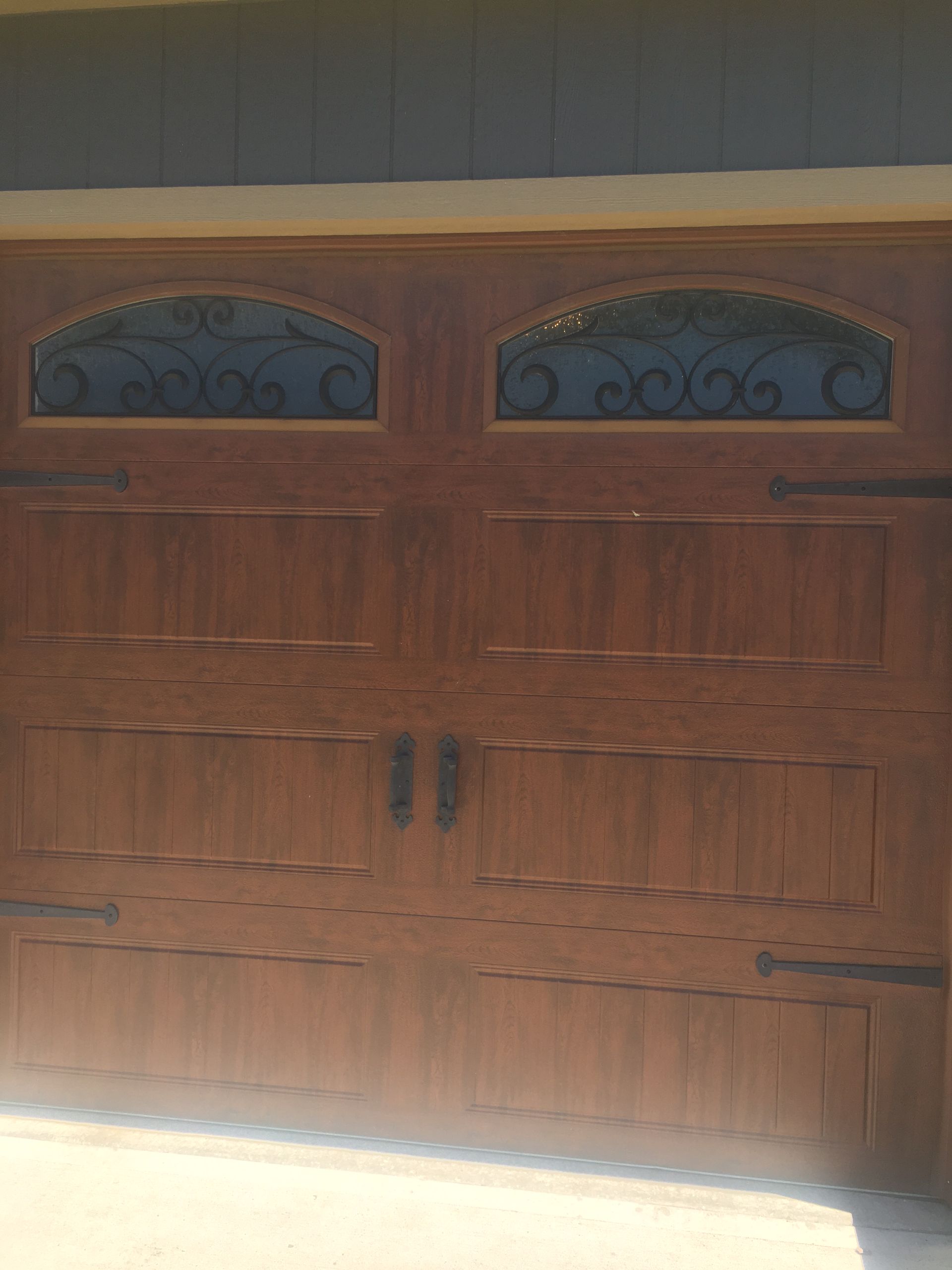 A close up of a wooden garage door with two windows.