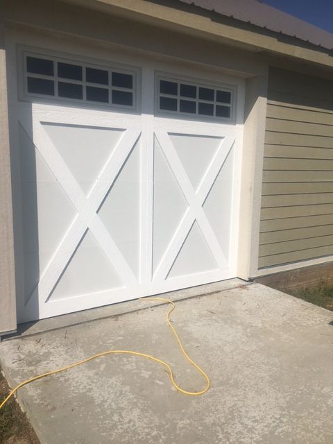 A white garage door with a yellow hose attached to it.