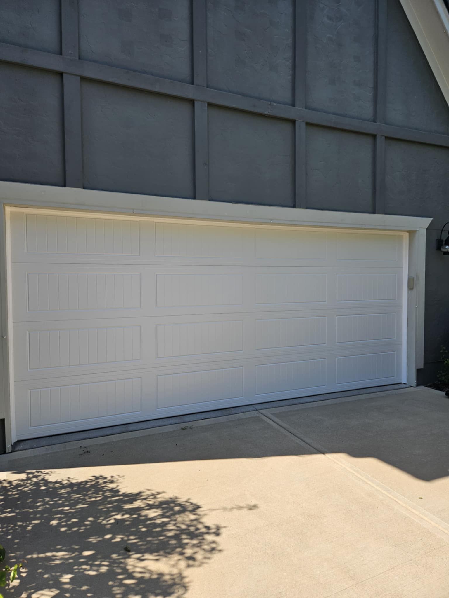 A white garage door is on the side of a house