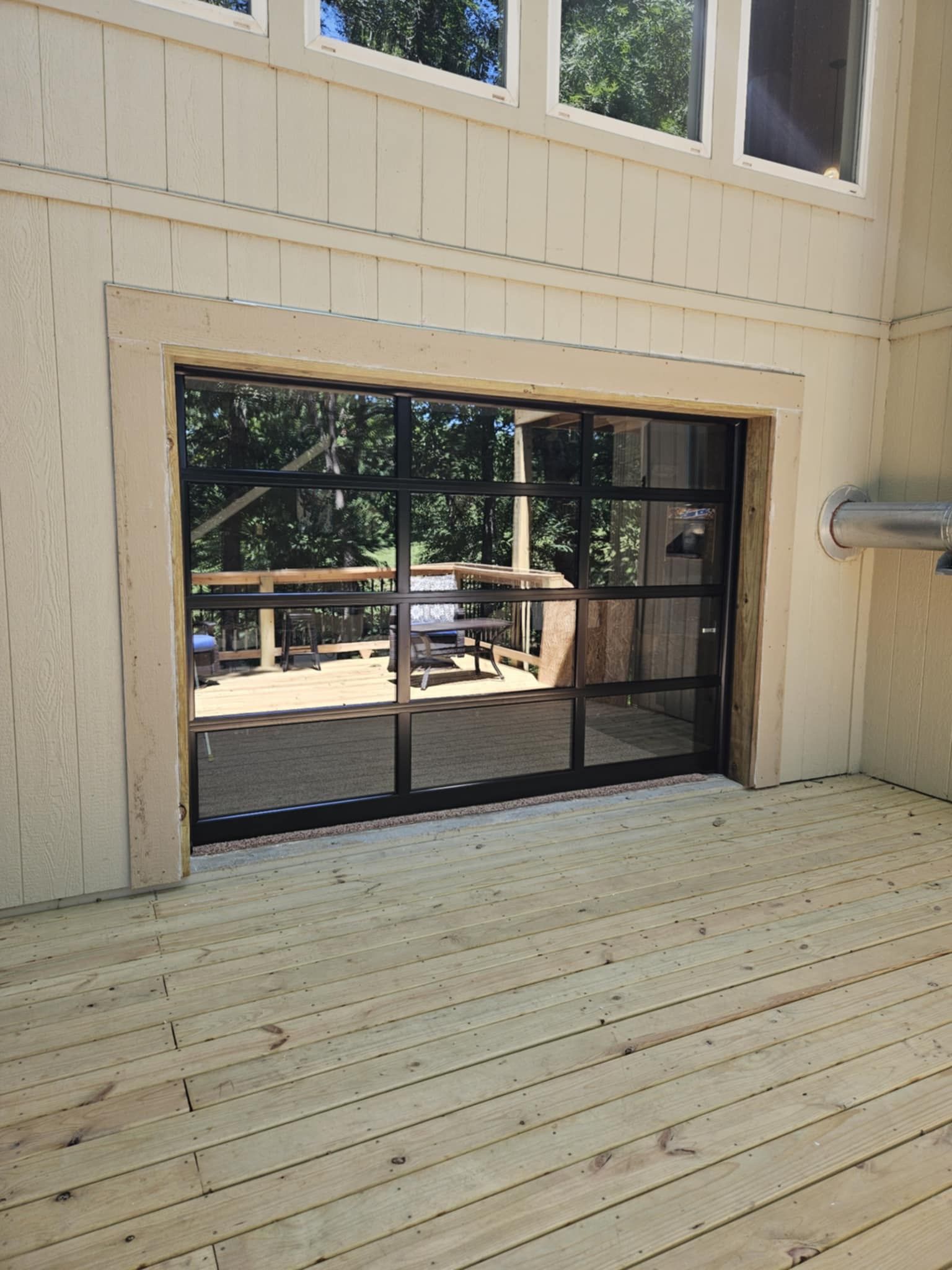 A large window in the side of a building with a wooden deck in the background.