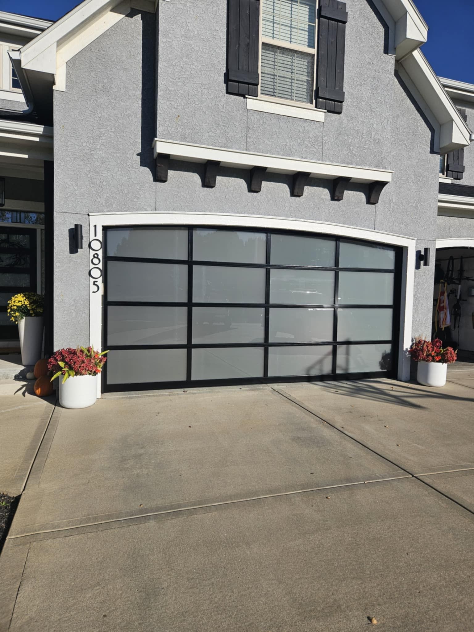 A gray house with a large garage door and flowers in front of it.