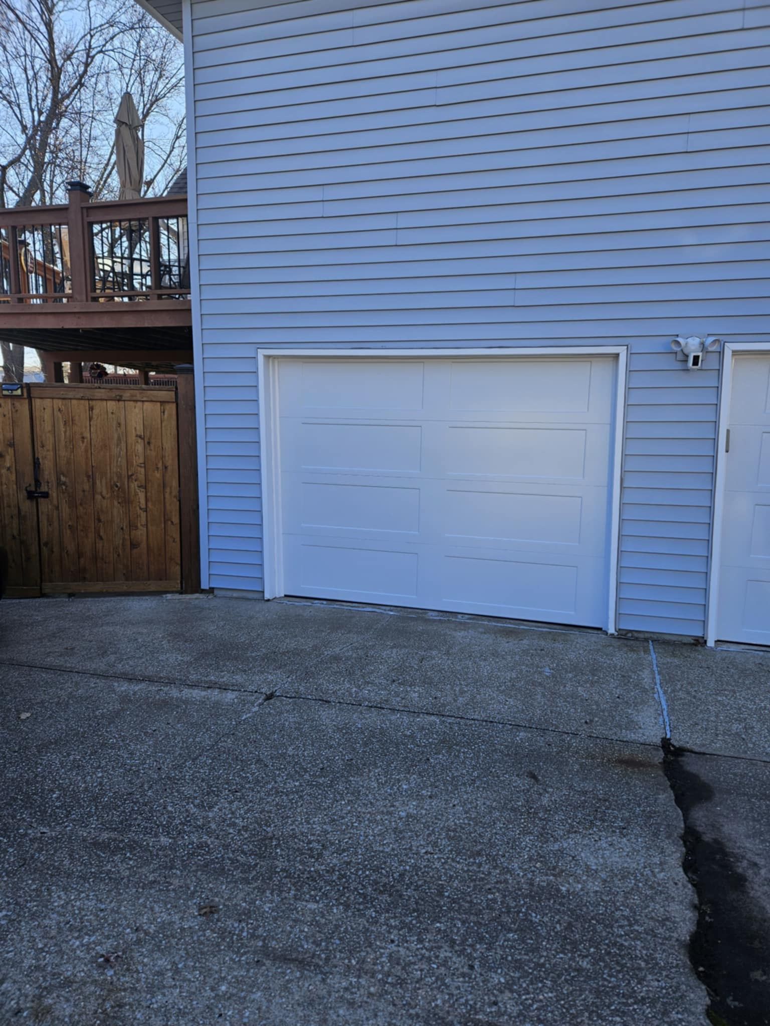 A blue house with a white garage door and a wooden fence.