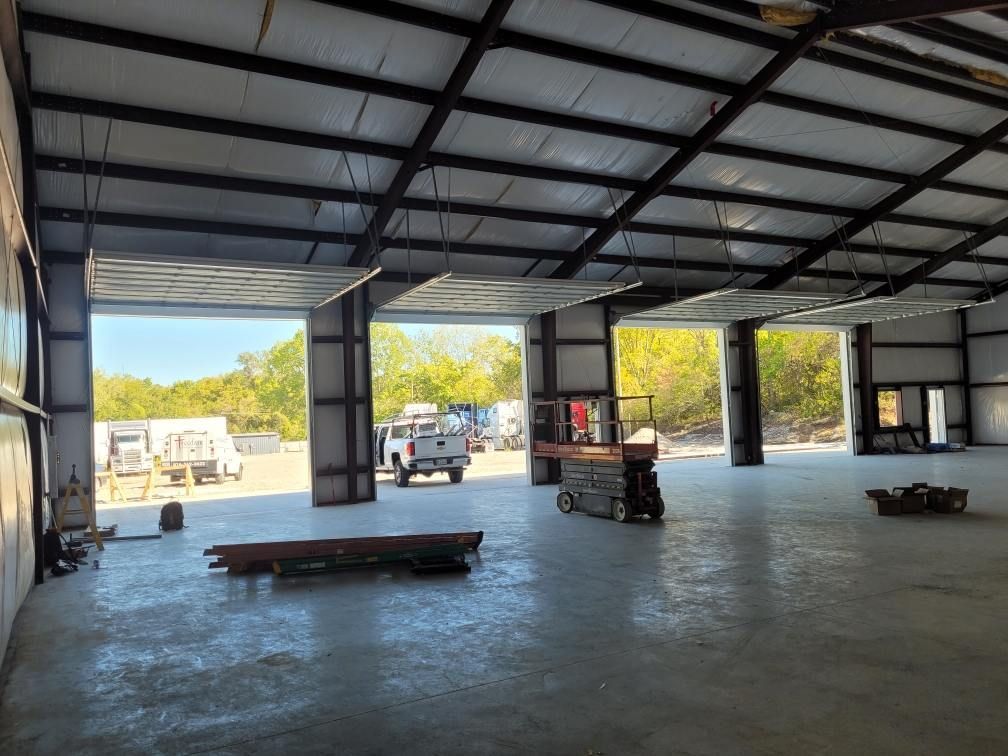 A large empty warehouse with a large garage door open.