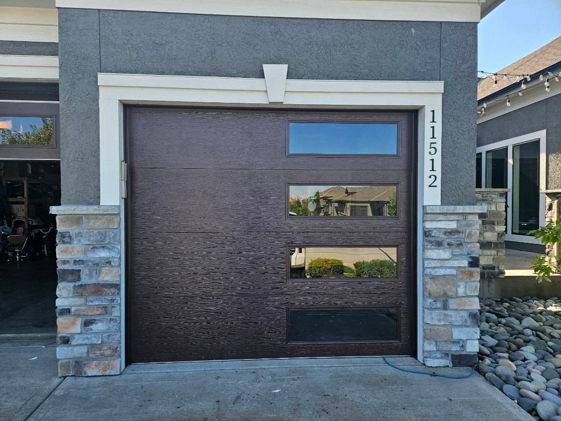 A brown garage door is sitting in front of a house.