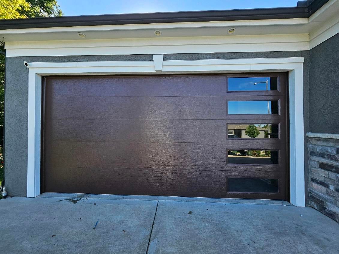 A brown garage door is sitting in front of a house.