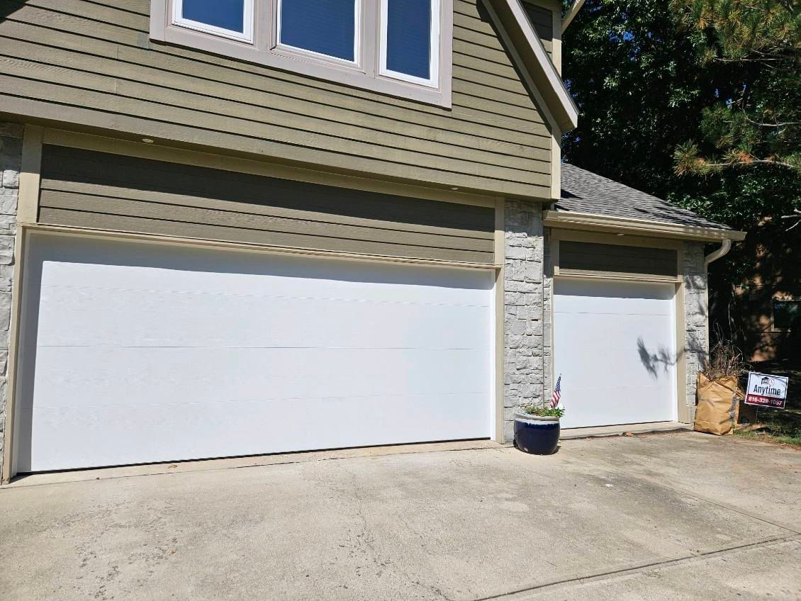 A house with two garage doors and a potted plant in front of it