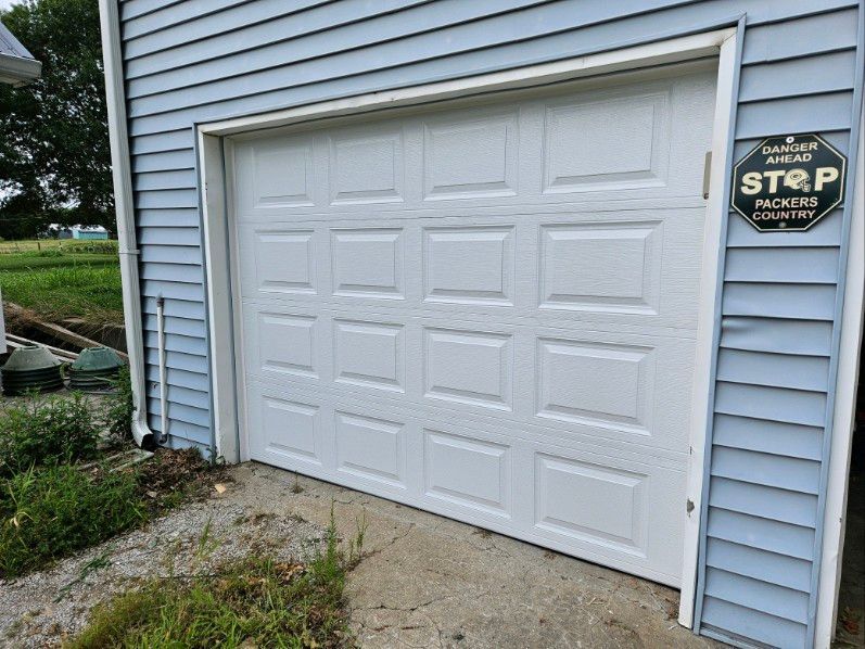 A white garage door is sitting on the side of a blue house.