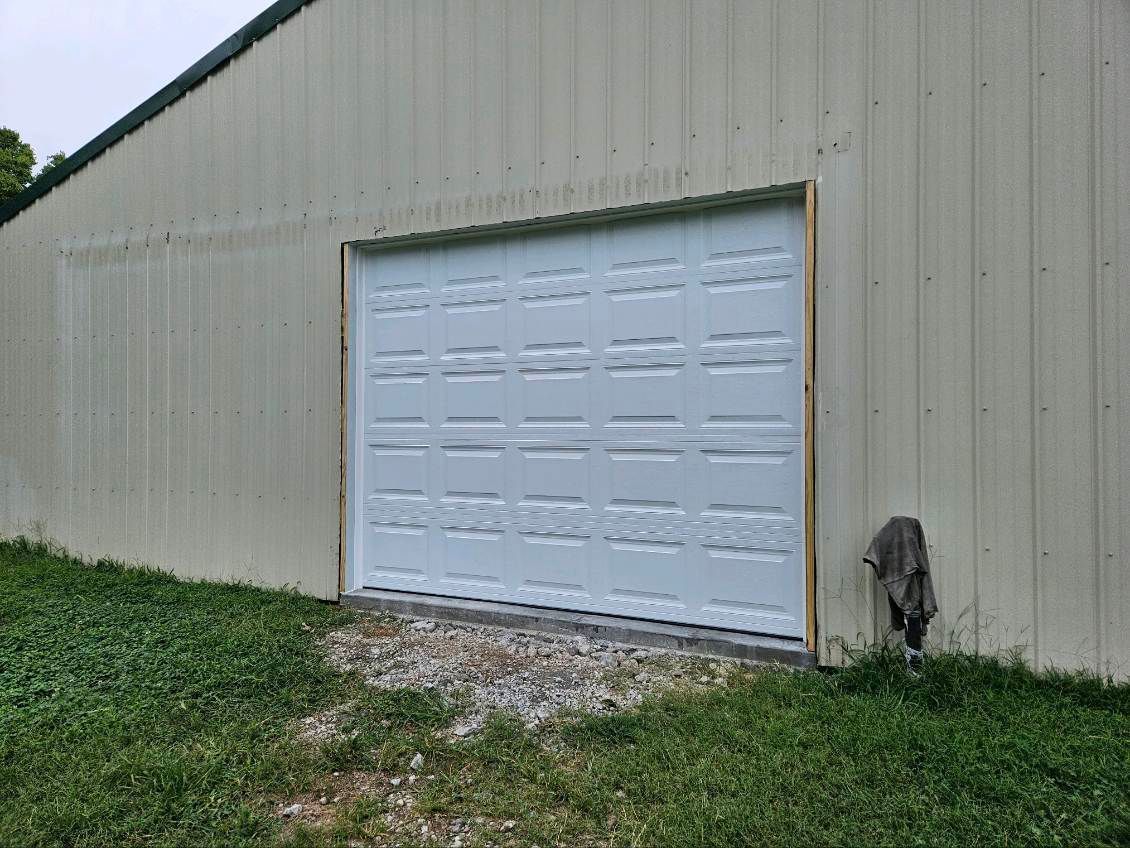 A white garage door is sitting on the side of a building.