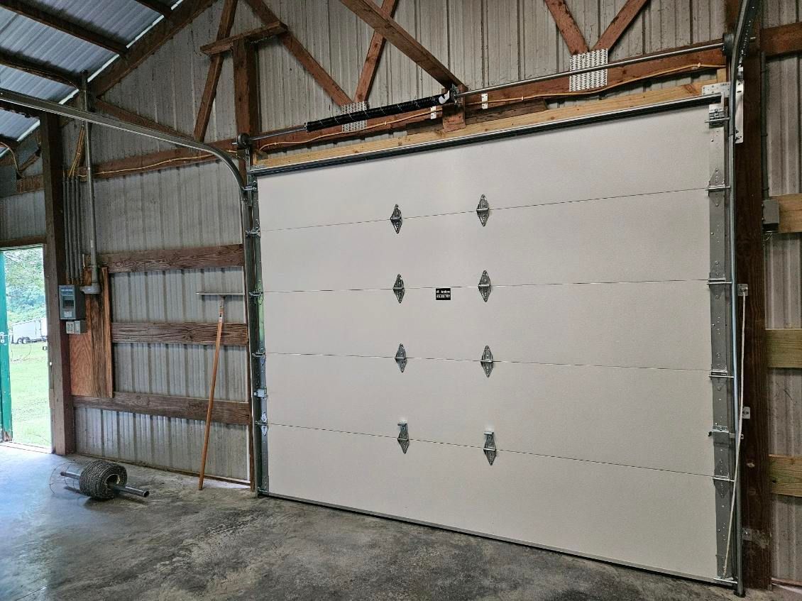 A white garage door is open in a barn.