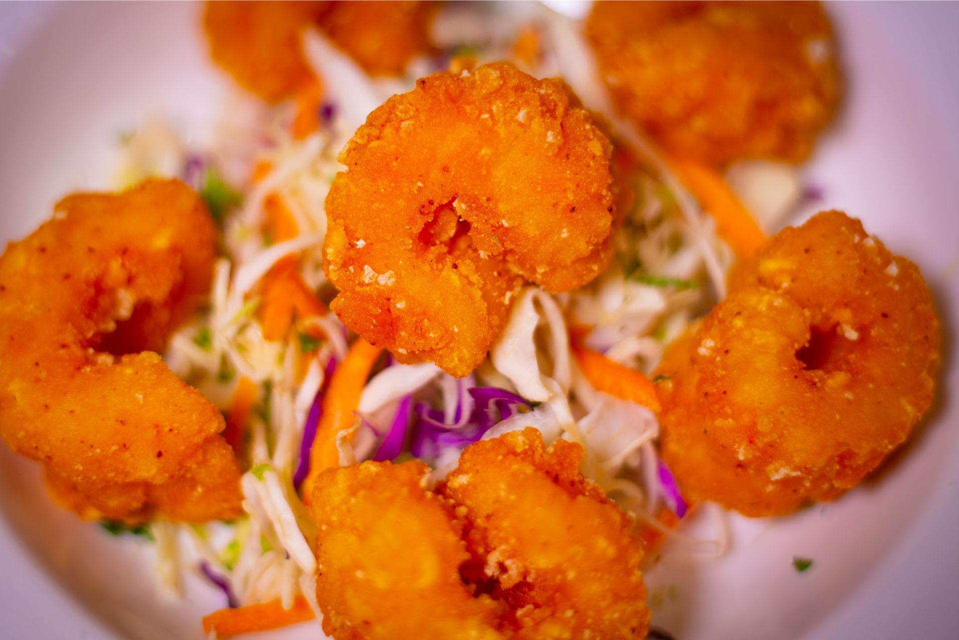 A white plate topped with fried shrimp and coleslaw.