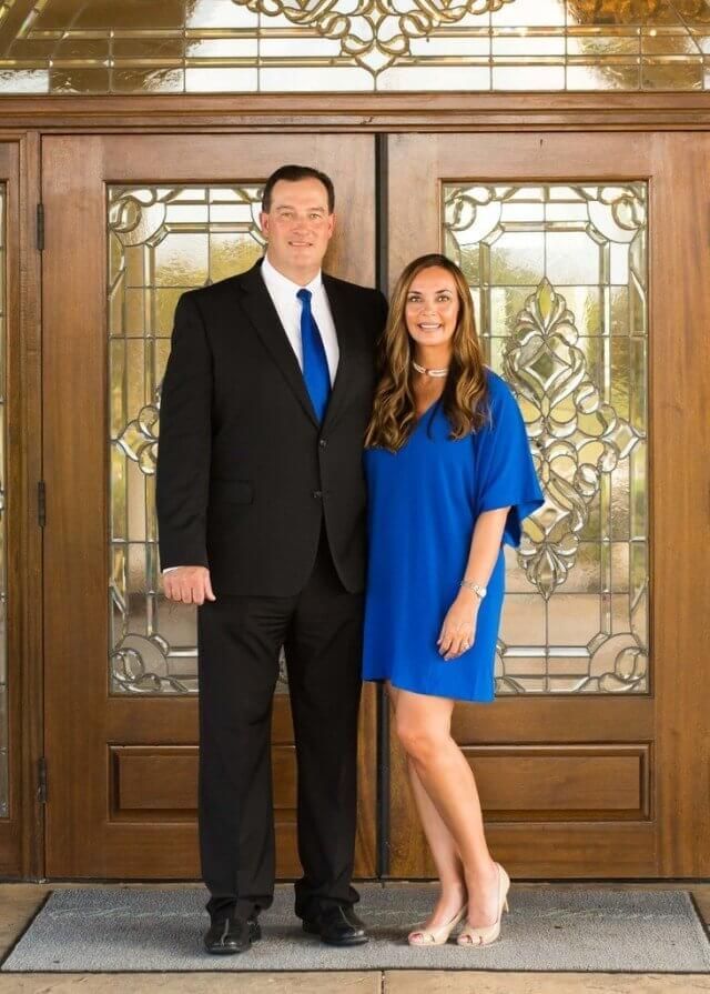 A man in a suit and tie is standing next to a woman in a blue dress.